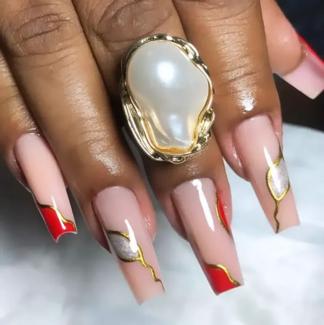 Nail art em vermelho e nude com filetes dourados